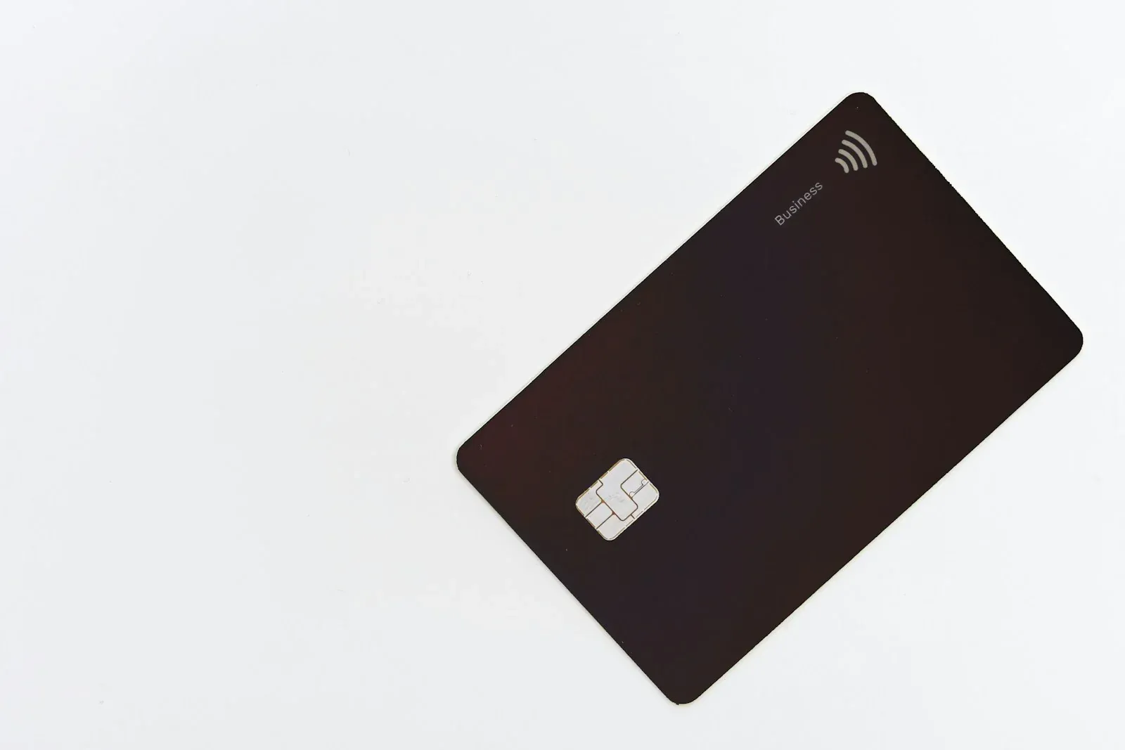 A black payment card with a chip on a white surface