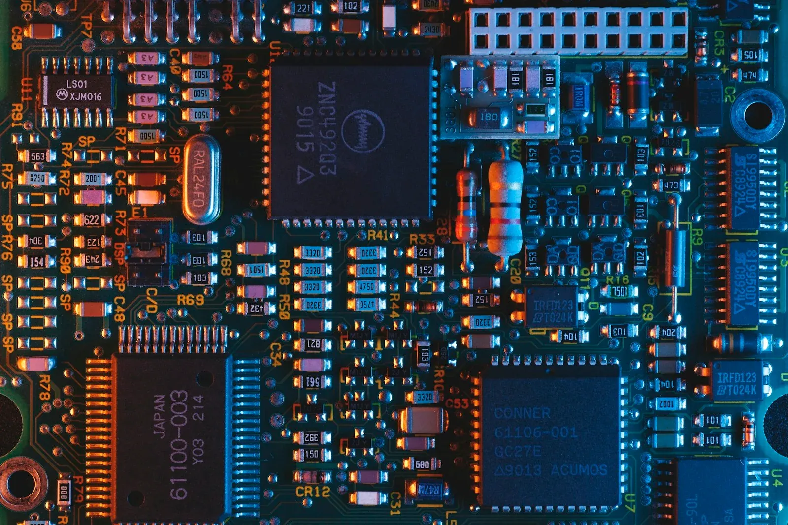 A detailed electronic circuit board lit in blue and orange