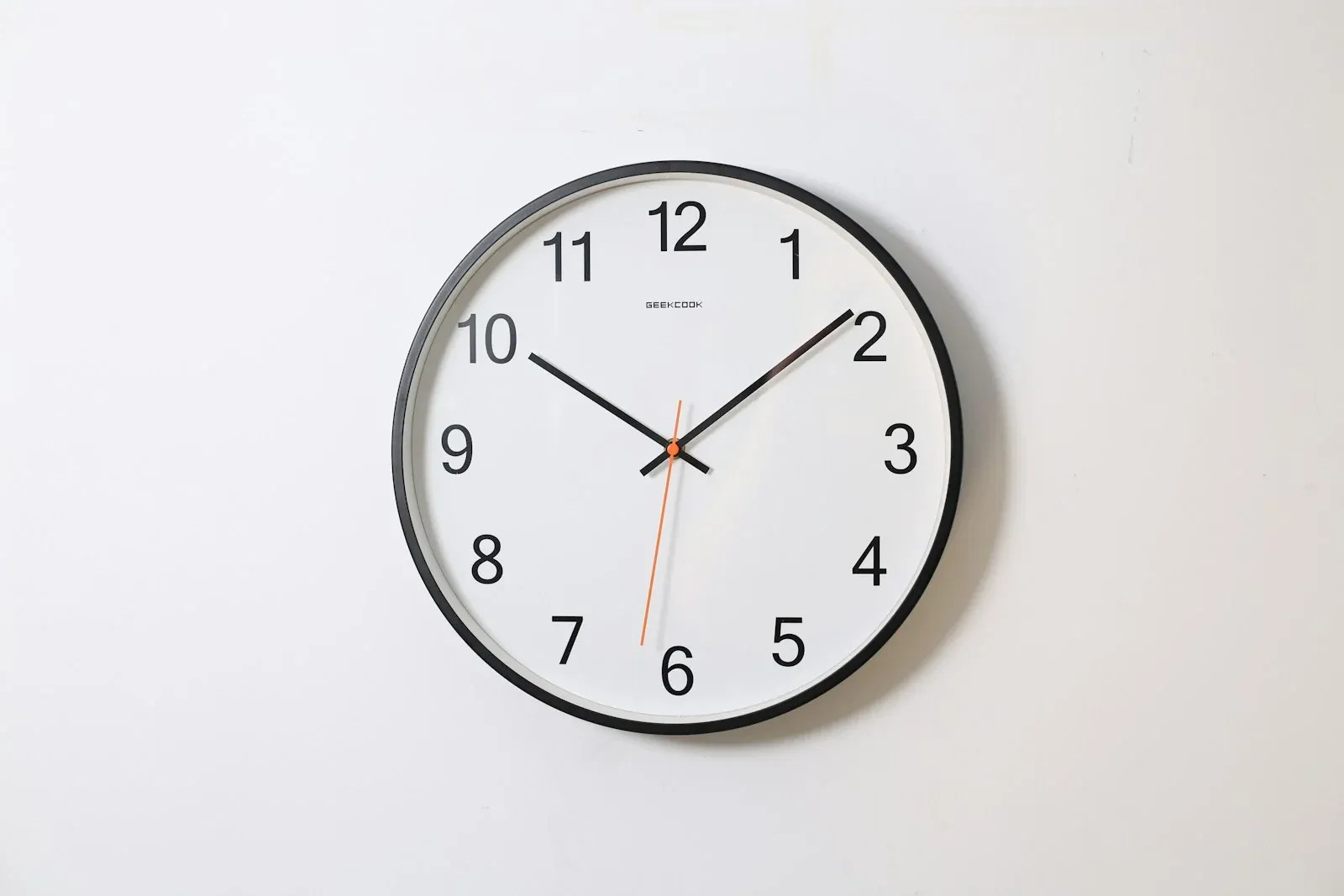 A round analogue wall clock with black hands and numerals