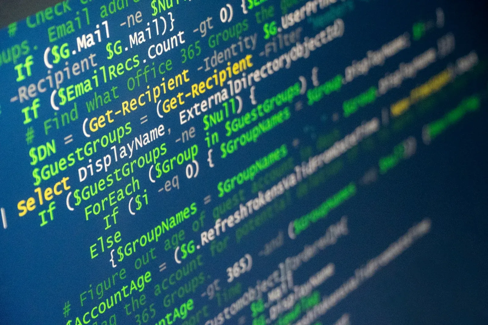 Close-up of a monitor displaying green and blue programming text