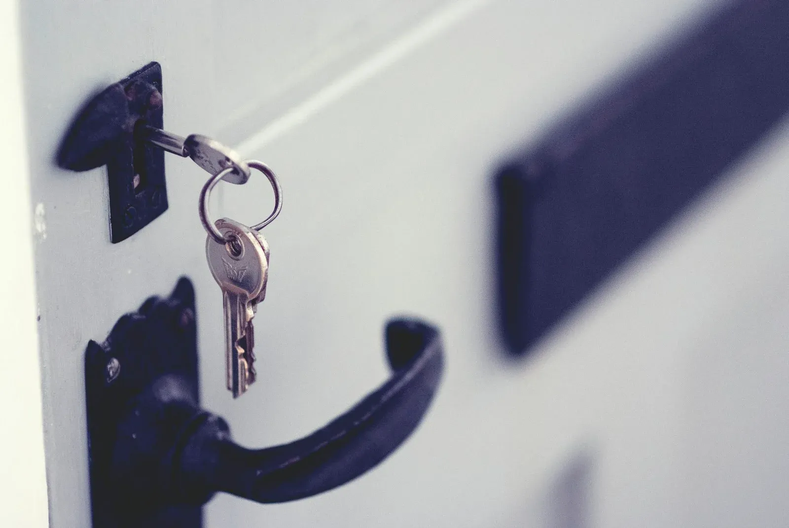A key in a white door lock beside a black handle