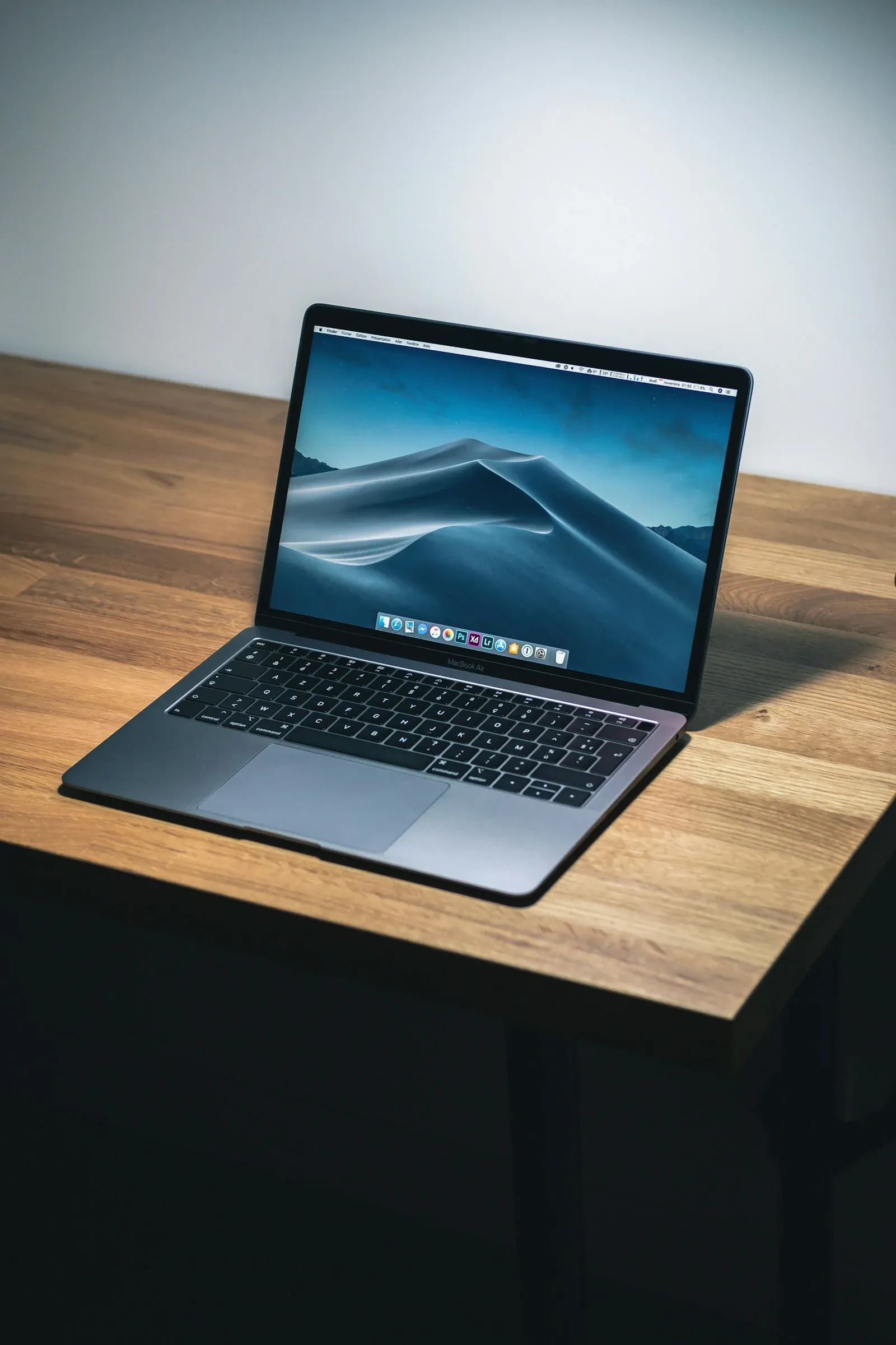 An open MacBook Air on a wooden desk