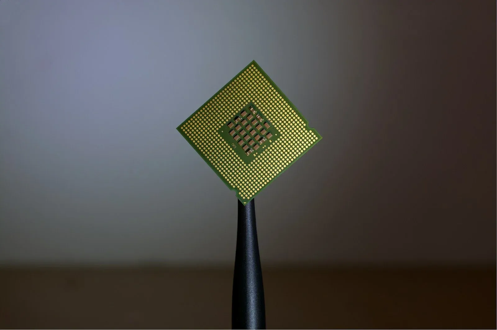 The underside of a computer processor held upright with tweezers