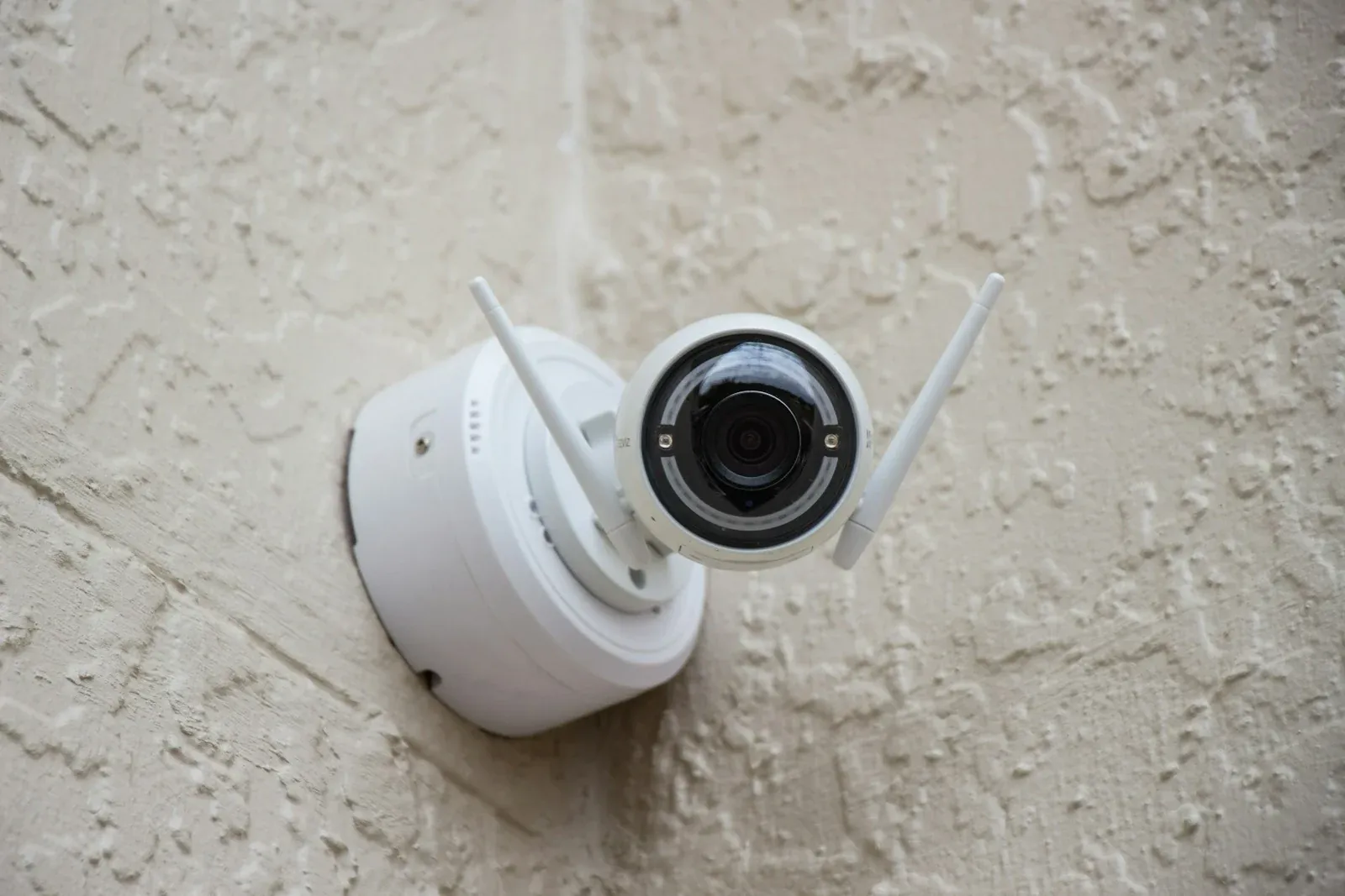 A white dome security camera attached to a textured wall